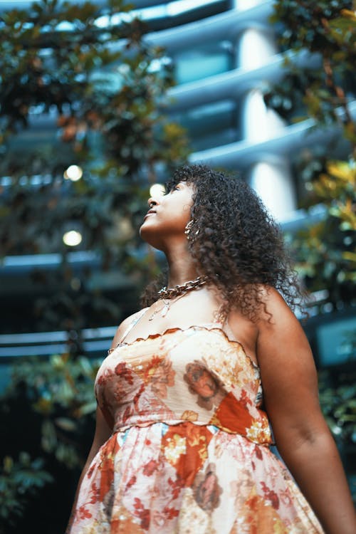 A Low Angle Shot of a Woman in Printed Dress Looking Up
