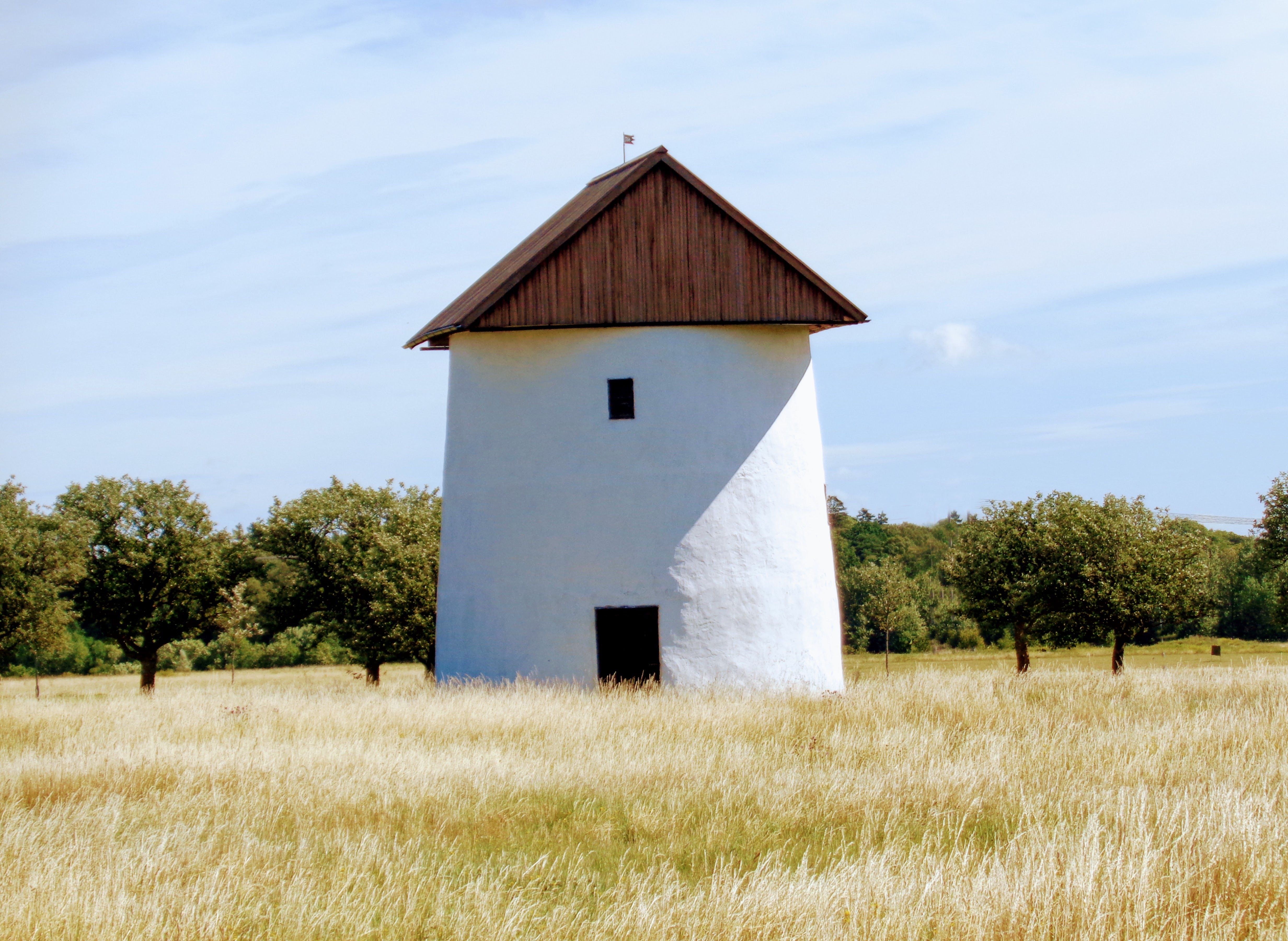 A classic windmill stands amidst a serene field in Gotland, Sweden's countryside.