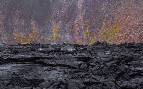 Free Close-up of textured volcanic rocks with vibrant green moss, showcasing geological features. Stock Photo