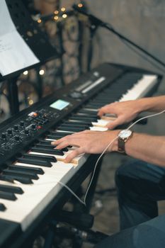 Close-up of musician's hands playing an electronic keyboard during an indoor session.