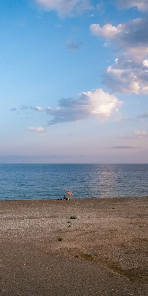 Brown Sand Near Body of Water under Blue Sky