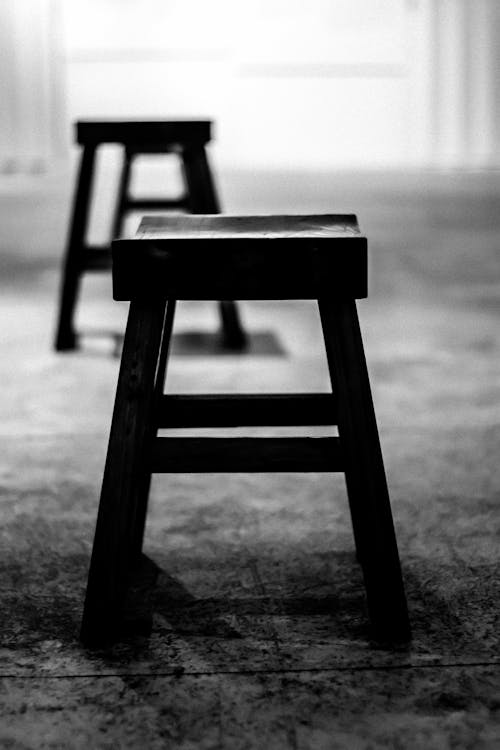 A Grayscale Photo of Wooden Chairs on a Concrete Floor