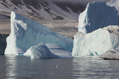 Iceberg on Body of Water Near Mountain 