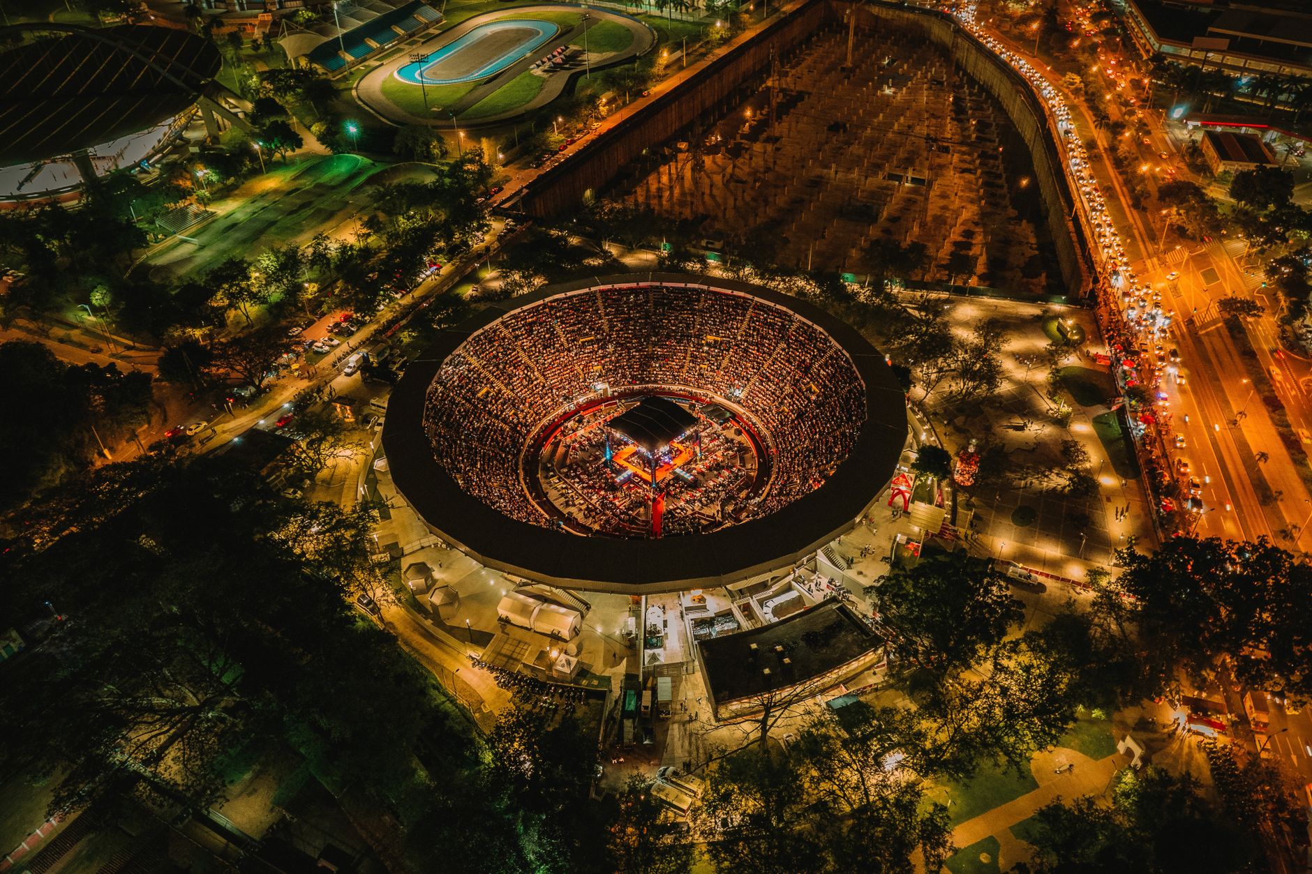 Stunning aerial shot of an illuminated stadium in Cali, Colombia at night, showcasing vibrant urban life.