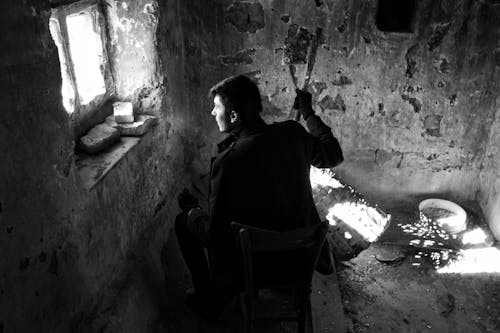 Man Sitting near Window in Black and White