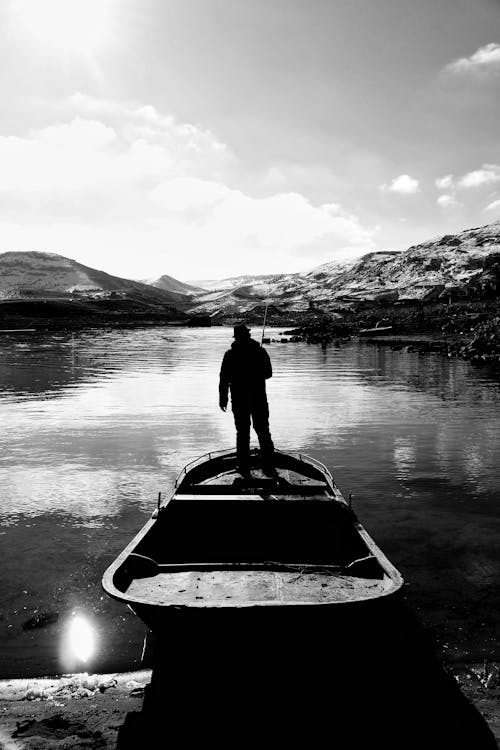 Grayscale Photo of Man Fishing in the Lake