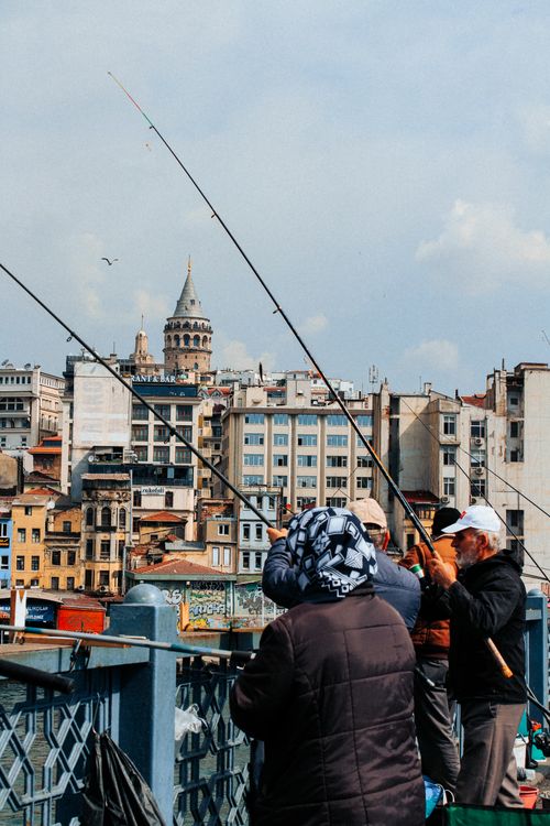 Free Fishermen casting lines on Istanbul's Galata Bridge with the iconic Galata Tower in the background. Stock Photo