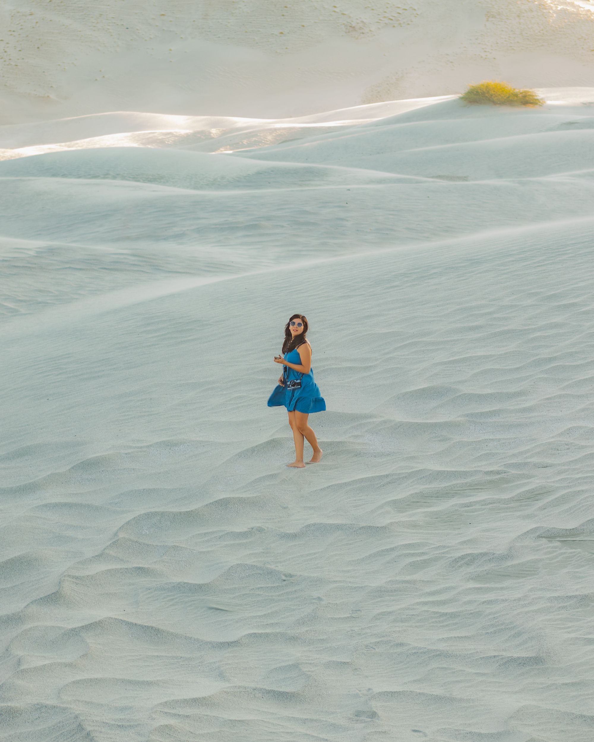 A Woman in Blue Dress Standing on White Sand · Free Stock Photo