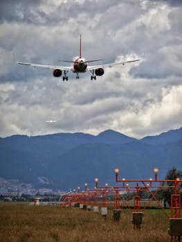 An airplane lands at Bogotá airport, framed by mountains and a dramatic cloudy sky.