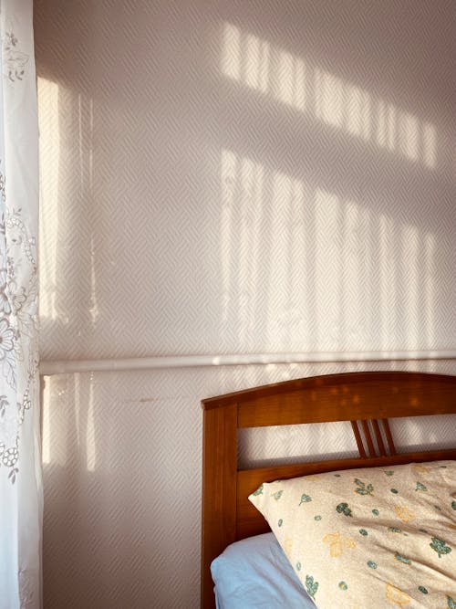 Free Wooden Bed in and Sunlight on a Pastel Pink Wall Stock Photo