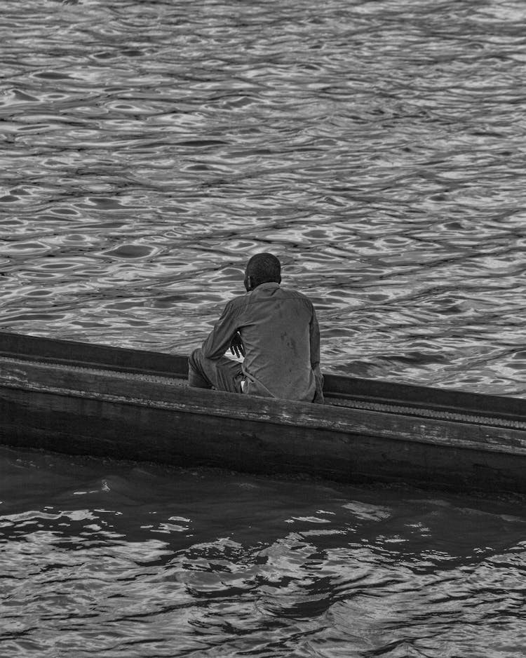 Man Sitting On Boat In Black And White