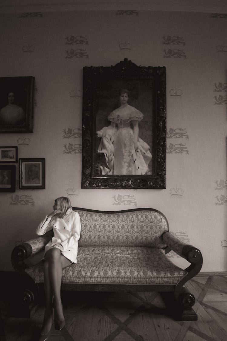 Woman Sitting On Couch Under Painting On Wall