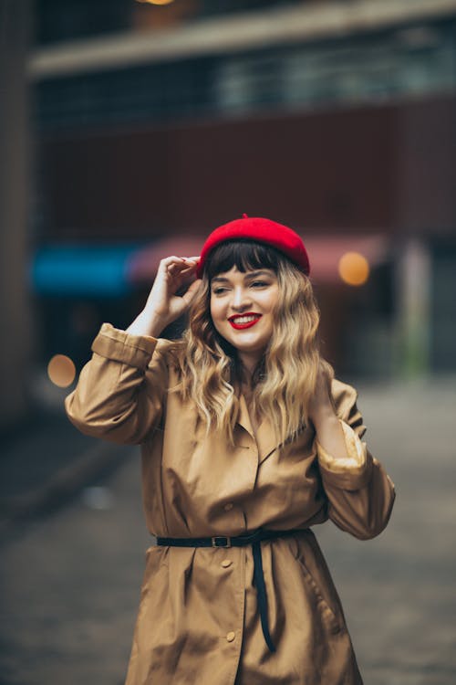 Woman in Trench Coat Standing and Touching her Red Beret 