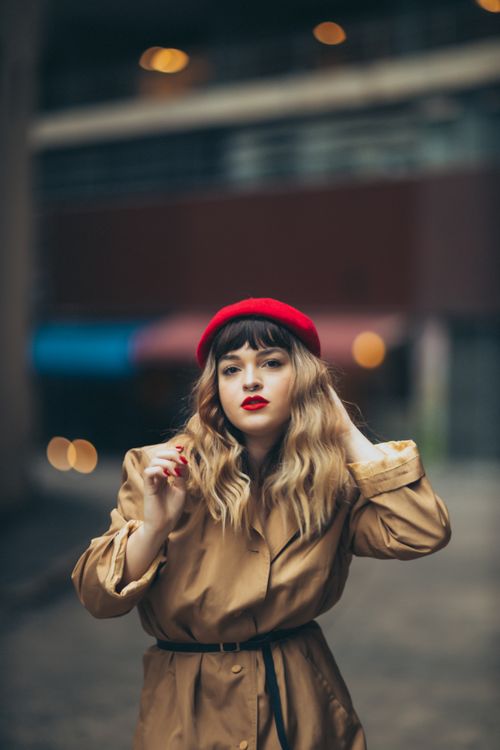 Free Fashionable woman with red beret and trench coat posing outdoors, embodying modern style and elegance. Stock Photo
