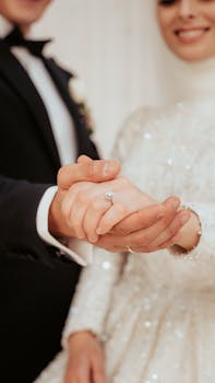 Close-up of a bride and groom holding hands, showcasing unity and love in a wedding setting.