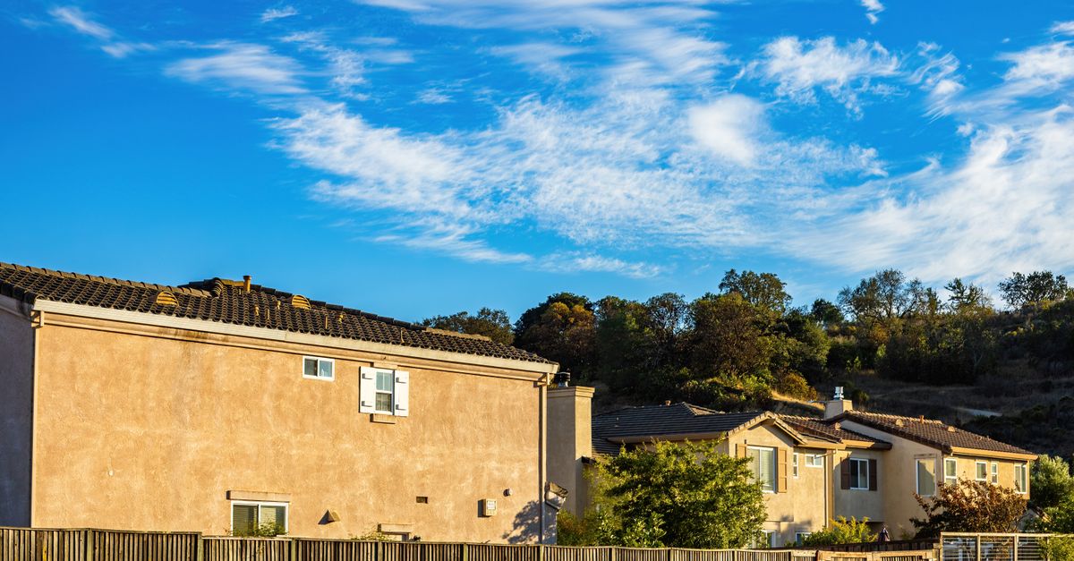 Charming suburban homes with clear blue sky and white clouds overhead.