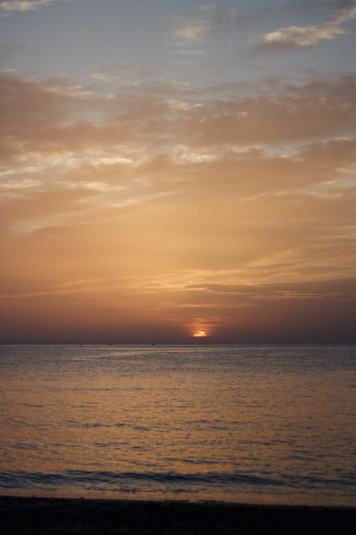 Free A beautiful sunset over a calm ocean horizon with warm colors filling the sky. Stock Photo
