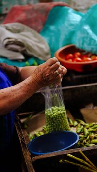 An adult hands packs fresh green beans at Ibagué market.