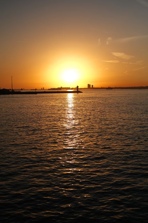 Free A serene sunset over the ocean with golden hues reflecting on the water. Stock Photo