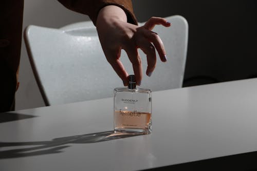 Hand Touching a Perfume Bottle