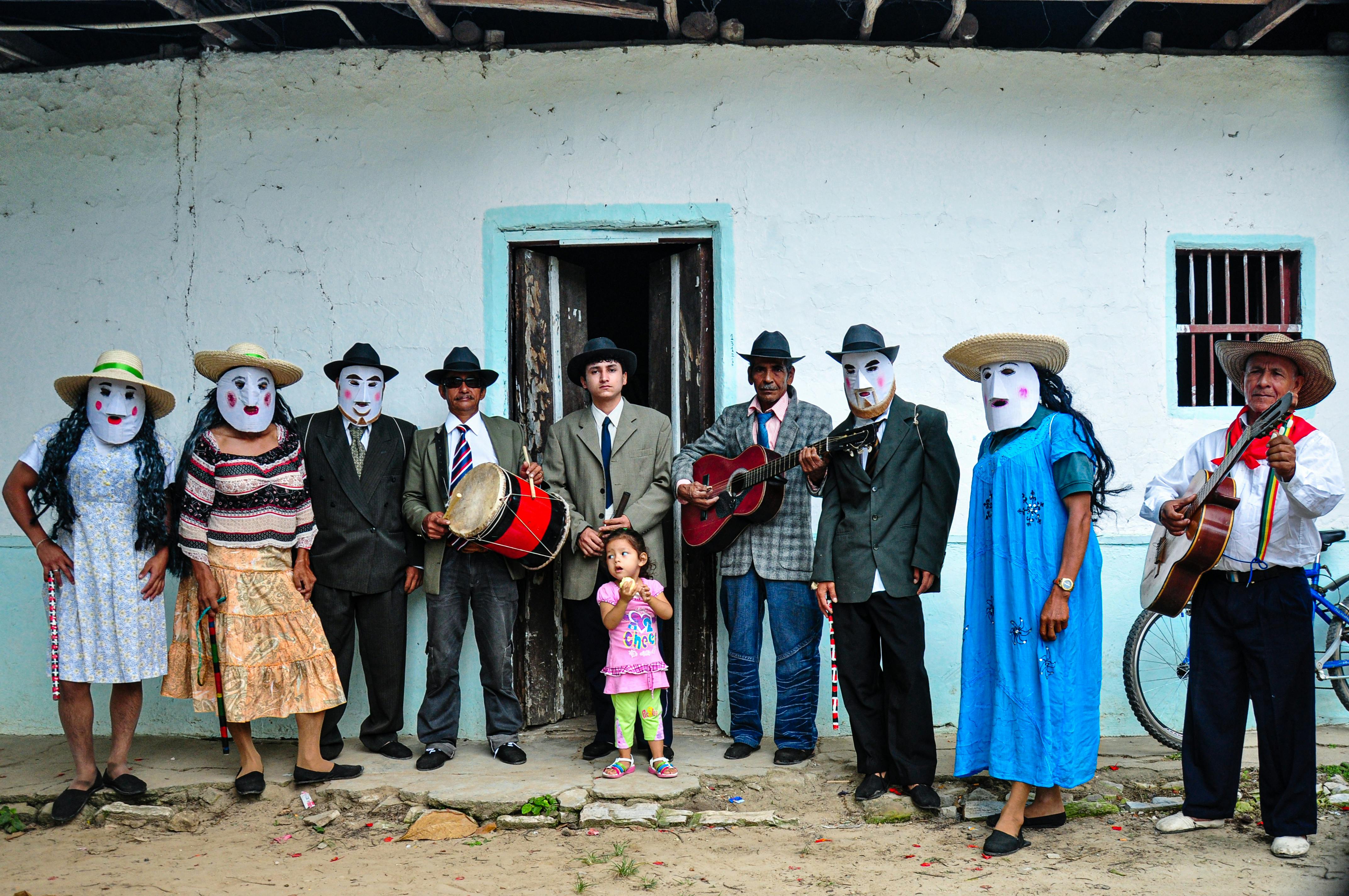 family wearing traditional costumes in front of a white house