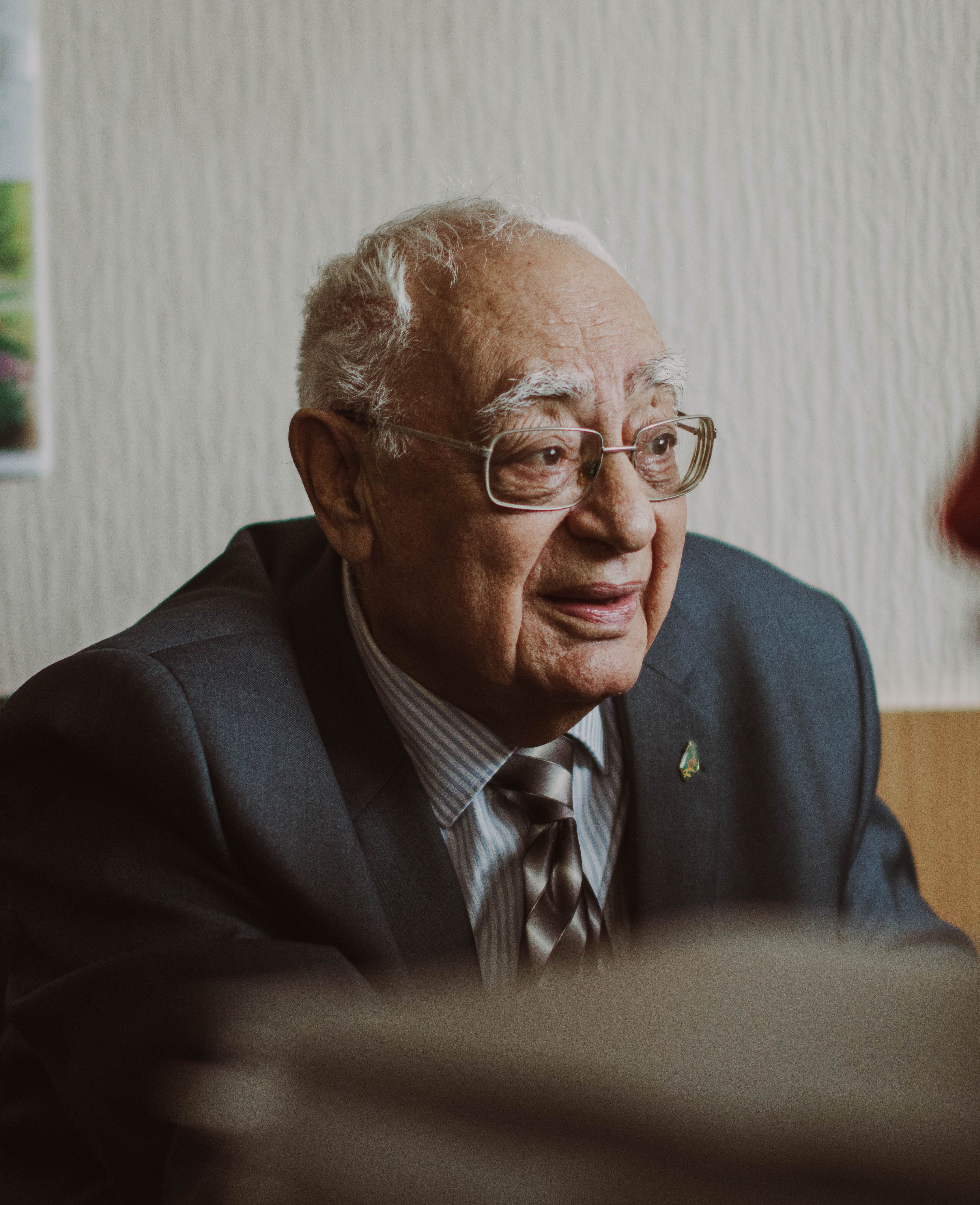 Portrait of an elderly man wearing a suit and glasses, evoking professionalism and wisdom.