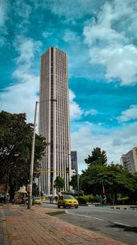 Urban scene featuring a modern skyscraper in Bogotá, Colombia under a vibrant blue sky.