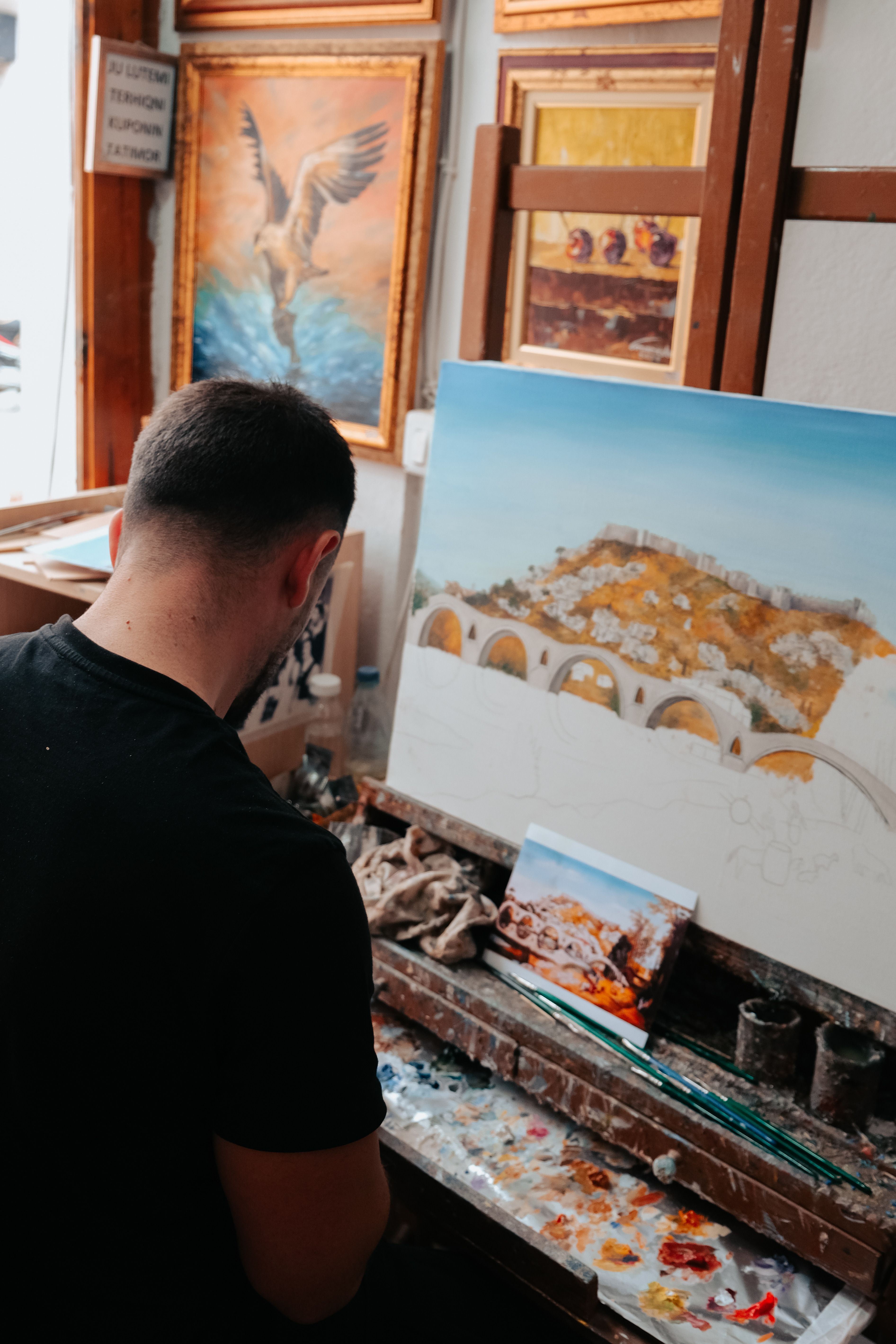 Man skillfully painting a landscape with acrylics in a cozy art studio setting.