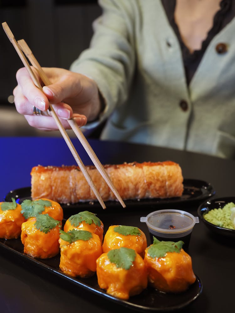 Closeup Of A Woman Eating Sushi With Chopsticks In A Bar