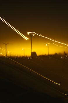 Creative long exposure of street lights with warm yellow tones, creating abstract motion blur against a night sky.