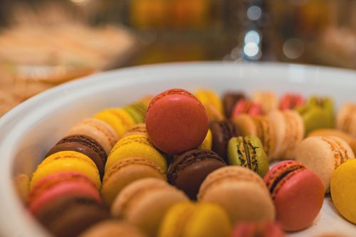 Free Close-up of a vibrant collection of French macarons in a ceramic bowl, showcasing delicious pastry variety. Stock Photo