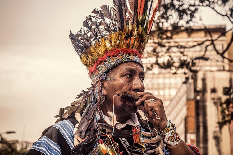 Man With Feathers Wreath Playing Instrument