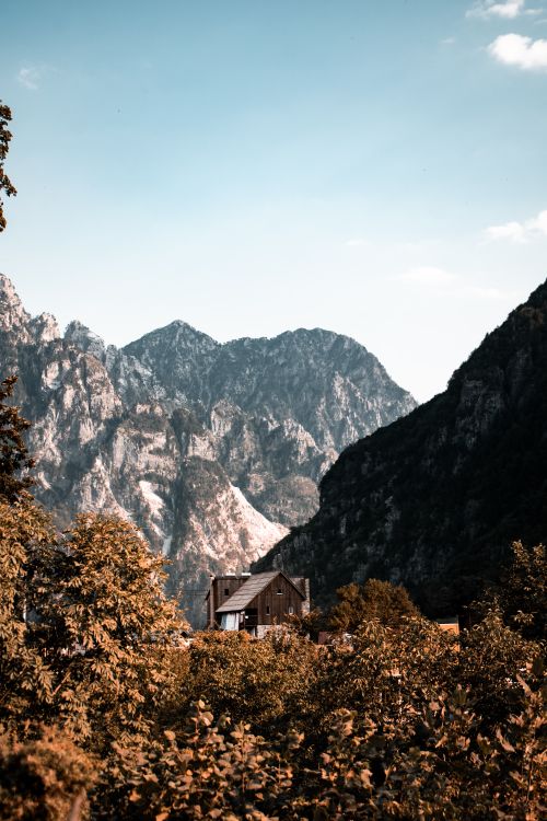 Free Wooden cabin nestled in Shkodër County, Albania, surrounded by majestic mountains under a clear blue sky. Stock Photo