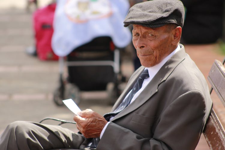 Elderly Man In Gray Suit Sitting On A Bench