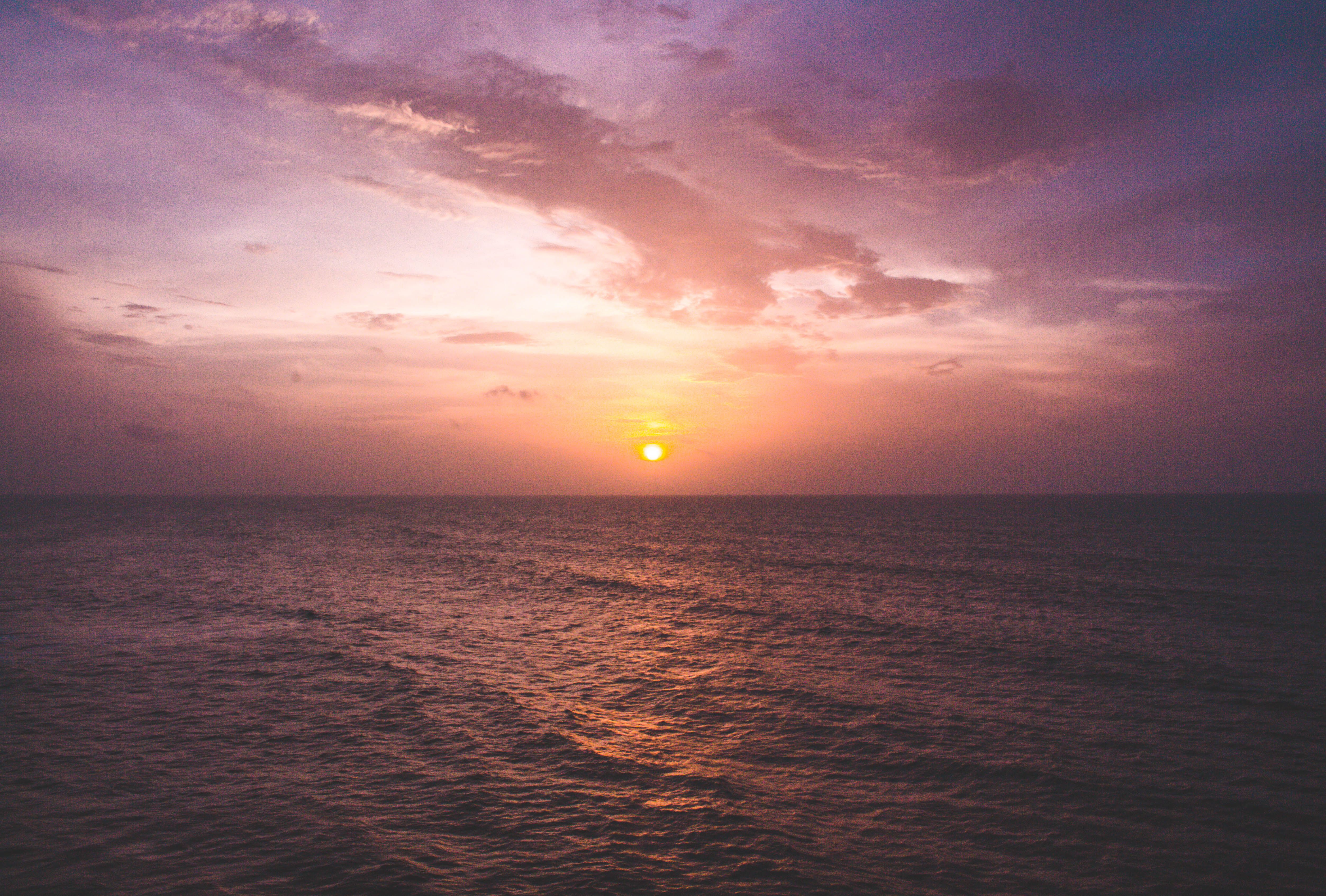 Stunning view of the sun setting over a calm ocean, creating a vivid and tranquil atmosphere.