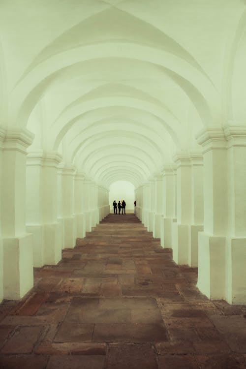 A White and Brown Concrete Hallway with a Group of People at the Back