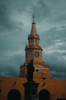 Stunning view of the iconic Clock Tower Gate in Cartagena, showcasing its unique architecture against a dramatic cloudy sky.