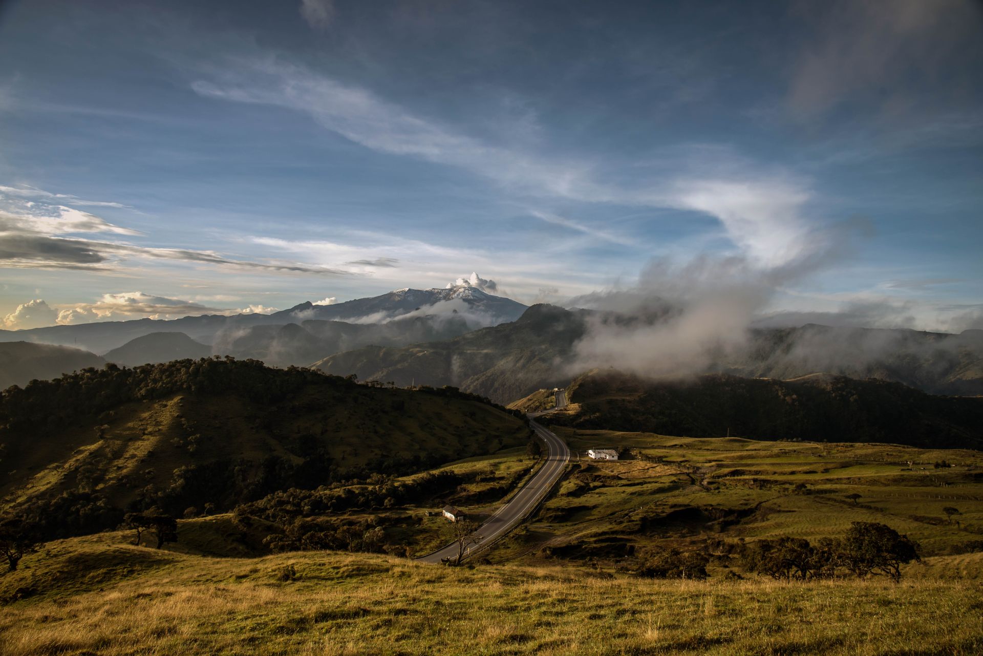Breathtaking landscape of mountain ranges and valley road in Manizales, Colombia under a clear blue sky.