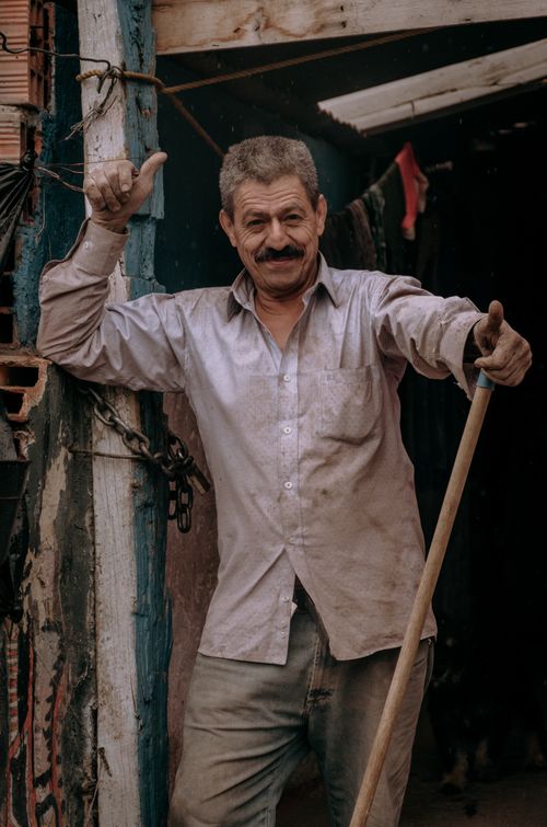 Free Portrait of a smiling elderly man with a mustache standing outdoors in Bogotá, Colombia. Stock Photo