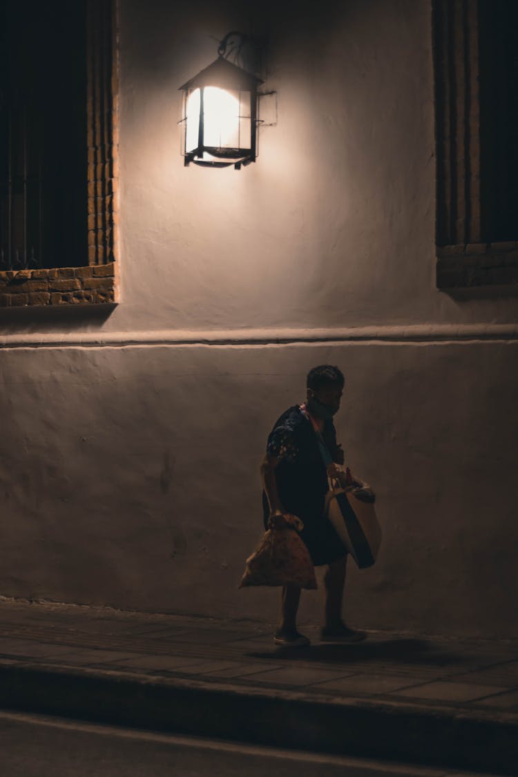 A Person Walking Alone On The Dark Street 