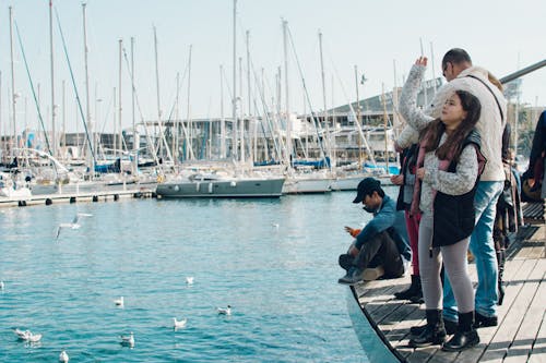 People Standing on Dock Fishing Near Boat Port