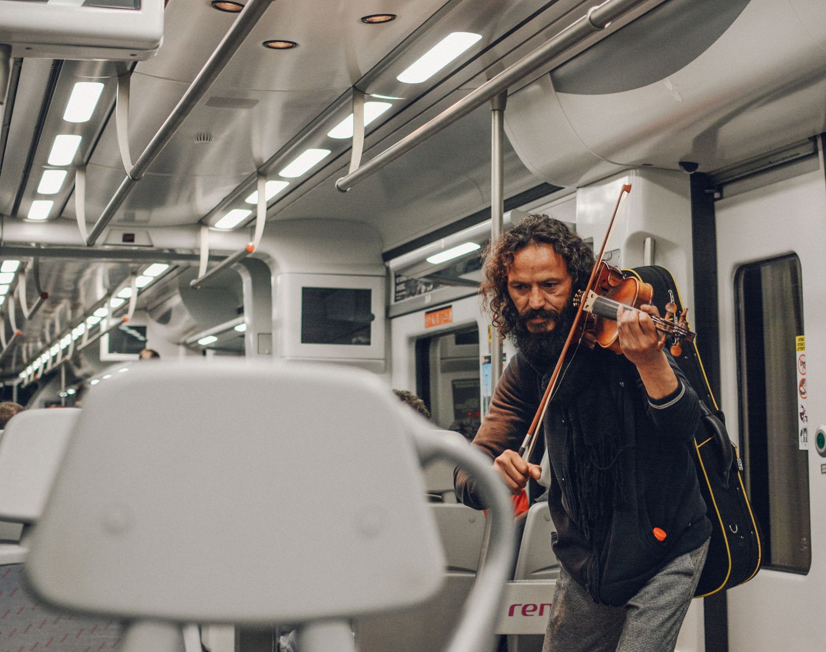 A male violinist passionately plays music inside a Barcelona train, capturing urban artistry.