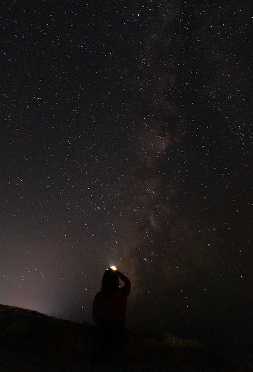 Silhouette of a Person Holding a Flashlight