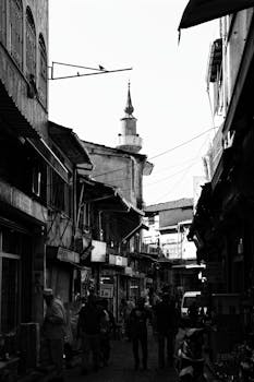 Monochrome photo capturing a bustling street scene with people and old buildings.