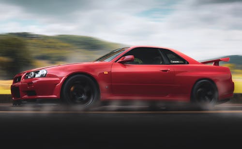 Selektive Fokusfotografie Des Roten Nissan Gt R R34 Skyline, Der Auf Straße Läuft