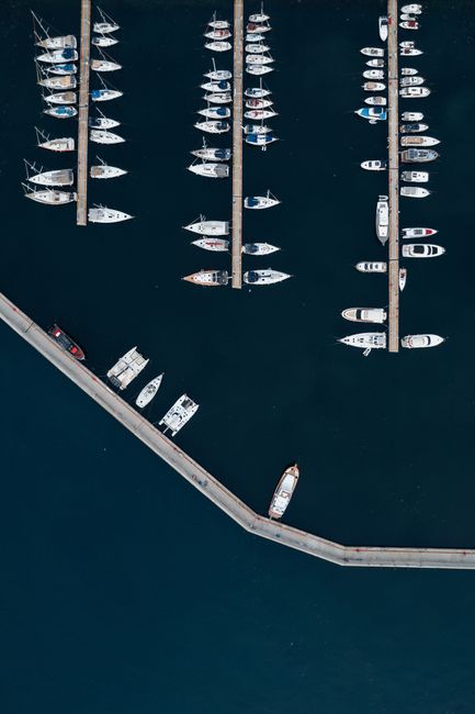 Aerial shot of boats and yachts docked in a marina with blue water.