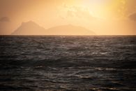 Peaceful view of the ocean with silhouettes of distant islands at sunset.
