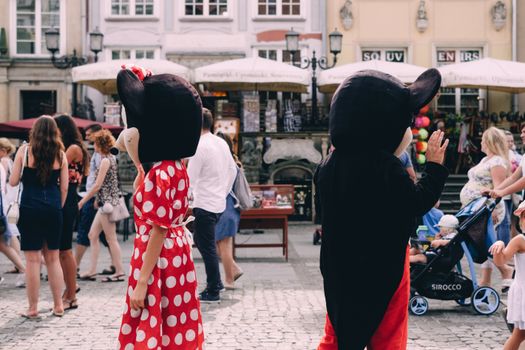 Costumed characters entertain a crowd on a sunny day in a vibrant outdoor setting.
