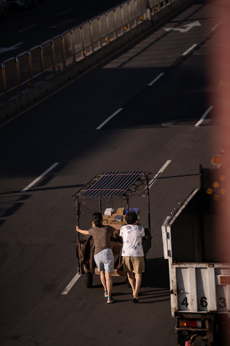 Women Pushing A Cart On Road