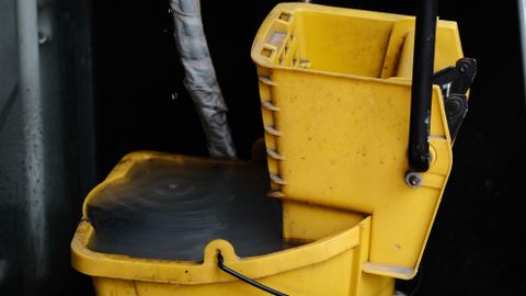 Close-up of a yellow mop bucket with caution sign, ideal for cleaning and maintenance themes.